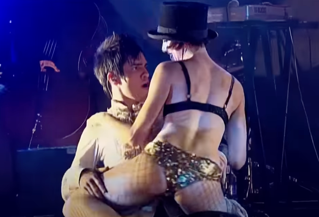 Brendon Urie and a Lucent Dossier Vaudeville Cirque performer staging a lap dance as part of the bridge for Panic! at the Disco's "But It's Better If You Do" at their 2006 Live in Denver show 
