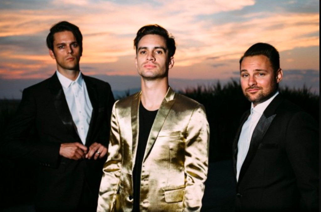 Brendon Urie in a gold suit as the sole remaining member of Panic! at the Disco, flanked by touring members Dallon Weekes and Kenneth Harris 